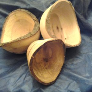 Three wooden bowls with bark on the edge sit on a blue background.