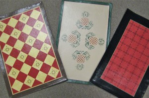 Three canvas floorcloths with different designs on each.
