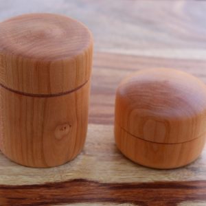 Two small cylindrical wooden lidded containers.