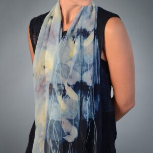 A woman poses in a silk scarf syed in different shades of blue.